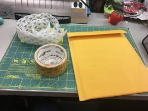 Image of a padded mailer, duct tape, and velcro sitting on a counter.