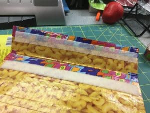 Image of a padded mailer being covered in duct tape., with velcro closure.