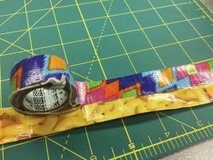 Image of thin tape being used to cover the edges of a duct tape strap.