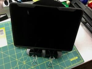 Image of iPad on a stand made of a bookend and two binder clips.