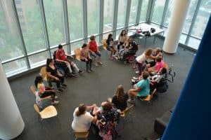 Image of a circle formed by ACES participants doing yoga in a glass-walled room