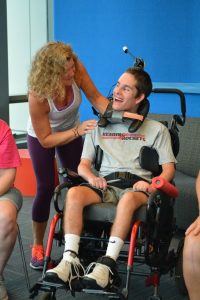 YOung man in wheelchair smiling at yoga instructor