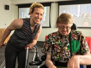 Image of woman with a wlaker and young AAC user in a wheelchair.