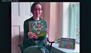 Woman reading ABCs Yoga and modeling in AAC device.