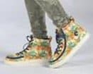 Feet with rainbow hightop sneakers. Ziipers around the full top of the shoe for accessibility.